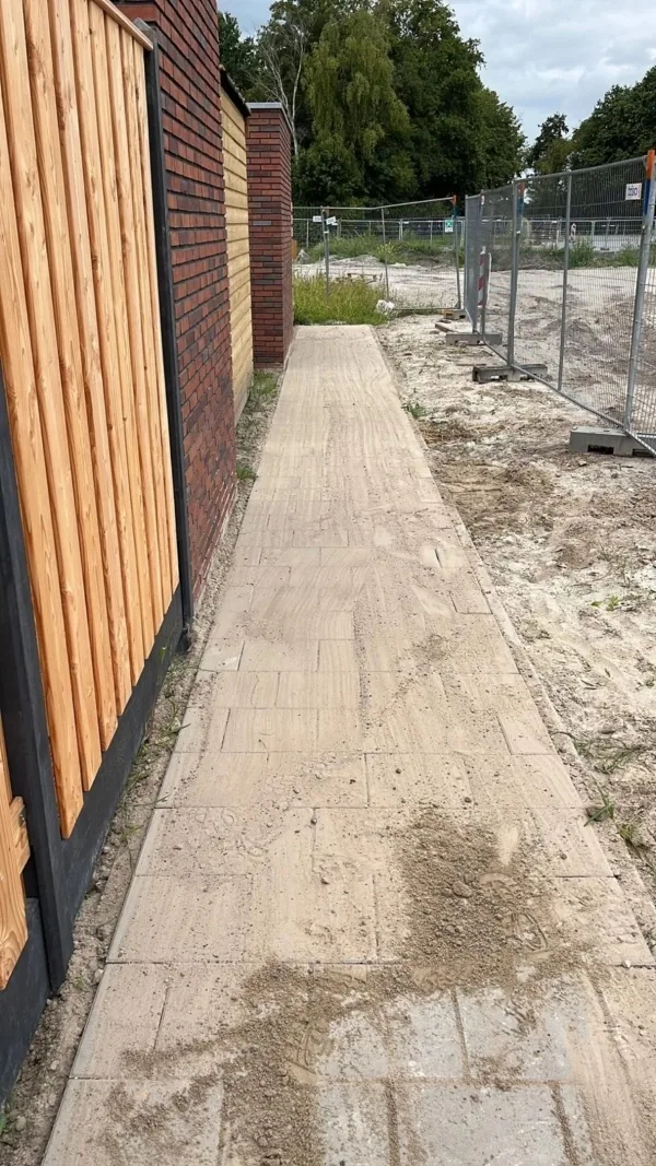Nieuw aangelegd pad van lichte tegels langs een gevel in Roden