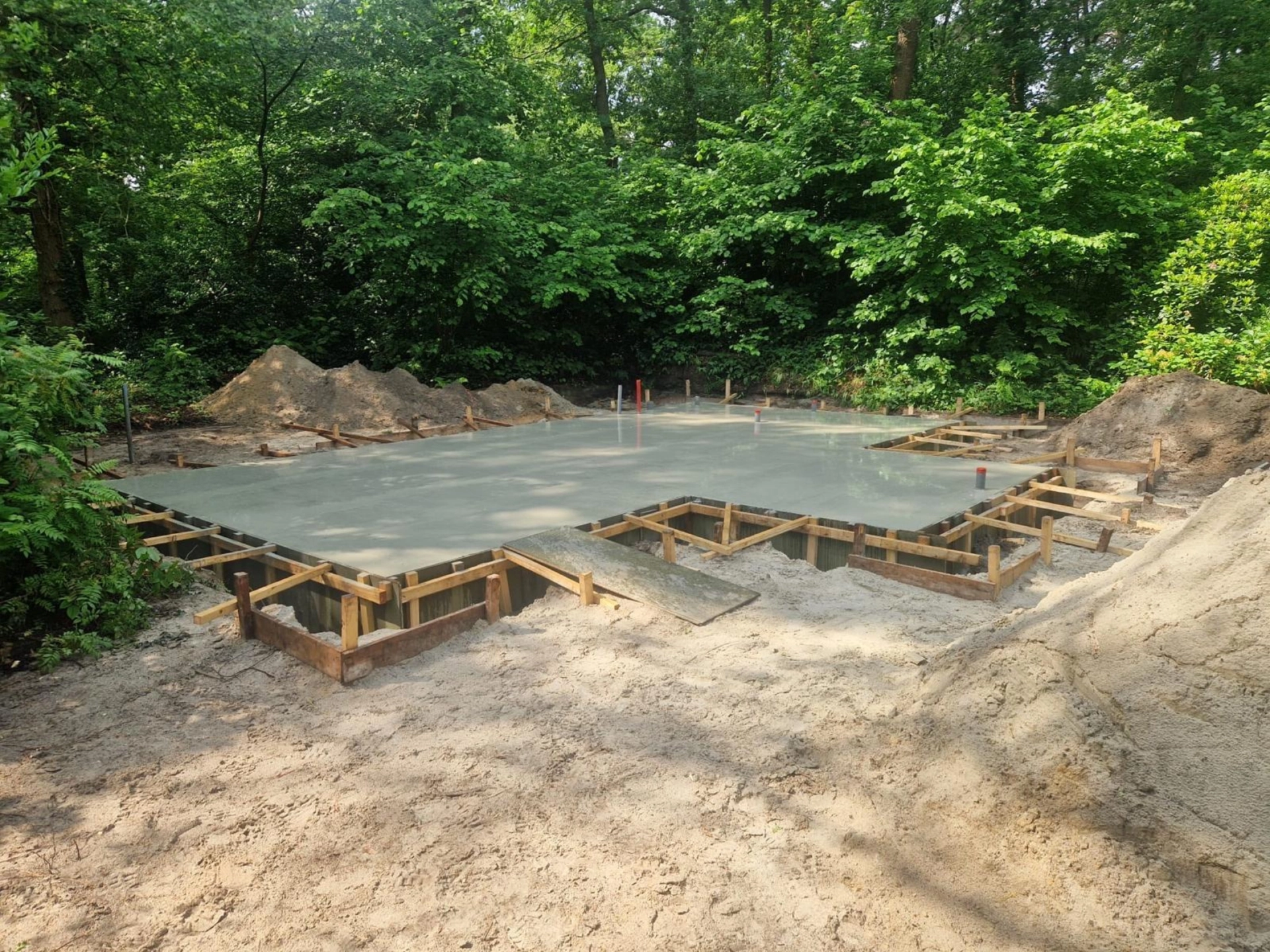 Nieuw gestorte betonnen fundering met houten bekisting in een bosrand